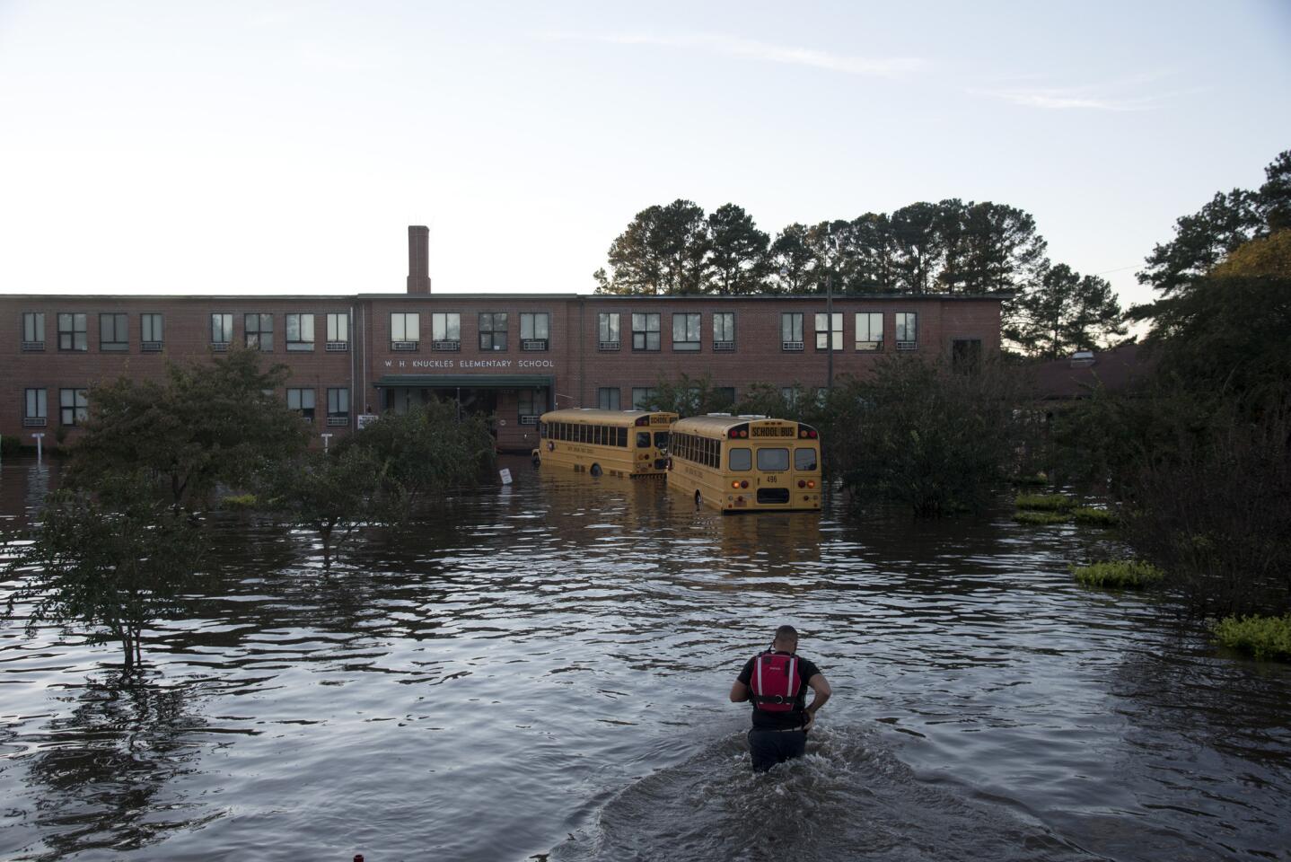 A volunteer firefighter with the Raynham-McDonald Fire Department makes his way through floodwaters after Hurricane Matthew to turn off the lights of a school bus in front of W.H. Knuckles Elementary School in Lumberton, North Carolina, on Oct. 10, 2016.