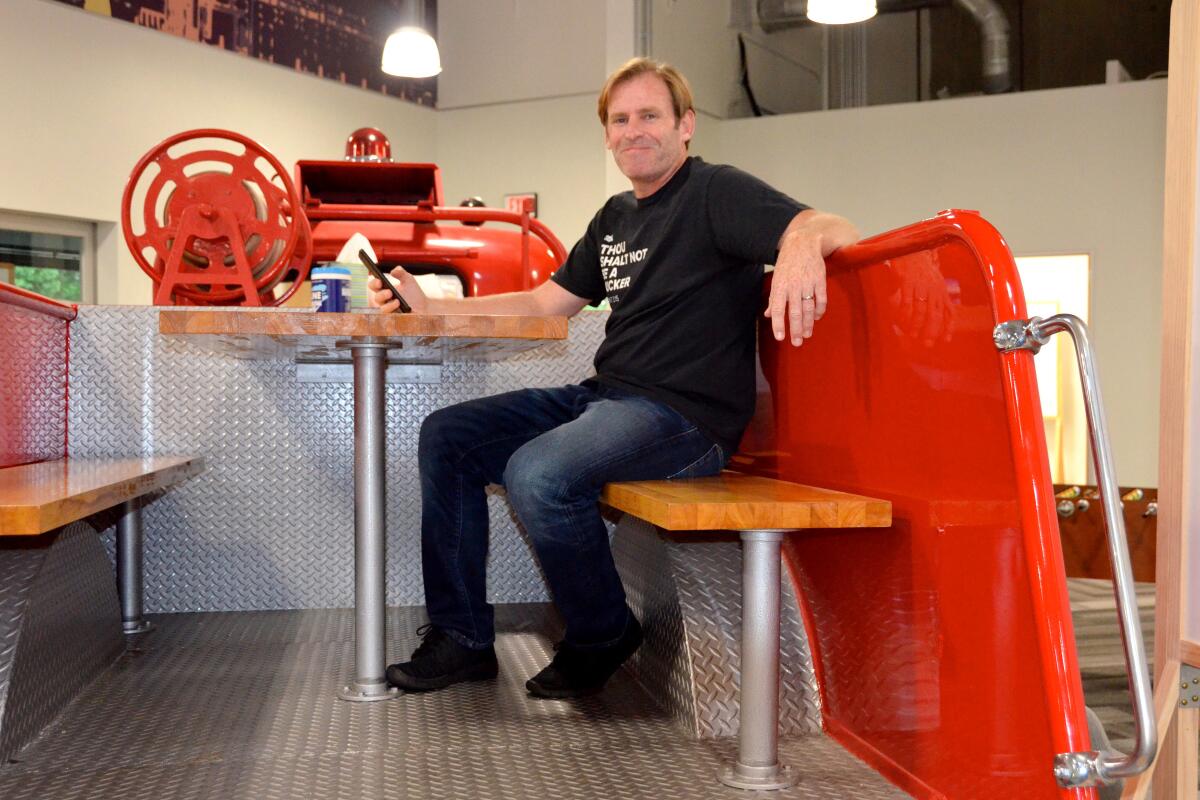 Aron North catches up on emails in the work space in a restored fire truck parked on the site of the Mint Mobile office.