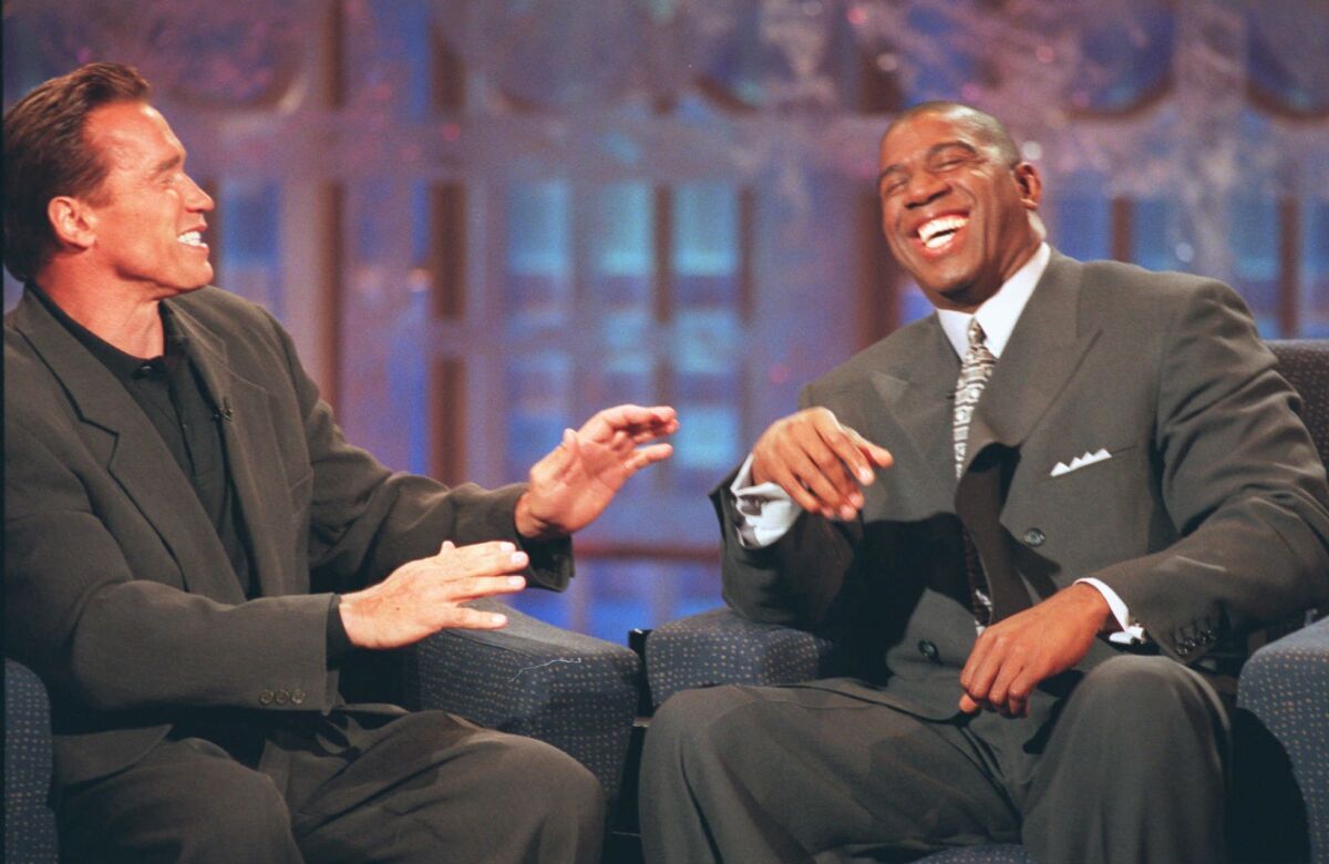Earvin "Magic" Johnson jokes with guest Arnold Schwarzenegger at the opening of his new talk show in Los Angeles, "The Magic Hour," June 8, 1998.