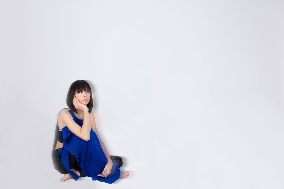 ピアニストのアリス・サラ・オットは、白い部屋の床に机の脚を座っています。