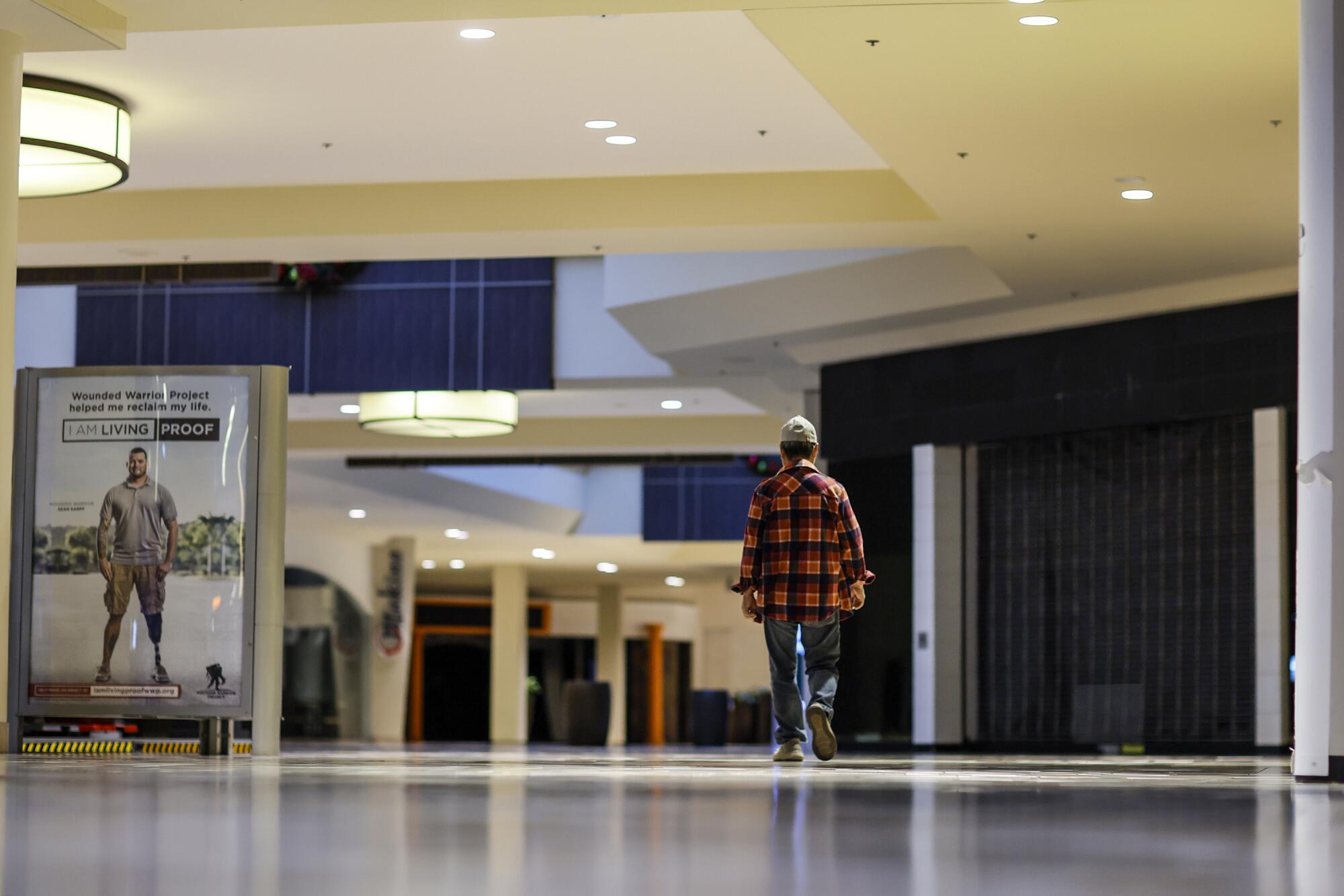 A mall walker passes by numerous shuttered stores near an empty Macy's at the Puente Hills Mall.