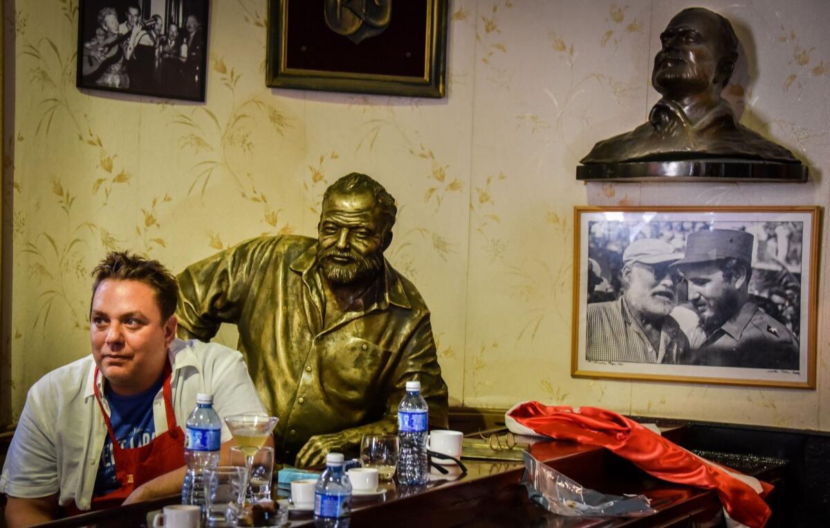 A bartender from the U.S. sits beside a statue of writer Ernest Hemingway at the Floridita bar in Havana in July. A contest to find who makes the best daiquiri took place beside the grave of a Cuban barman who was the owner of the Floridita in Havana.