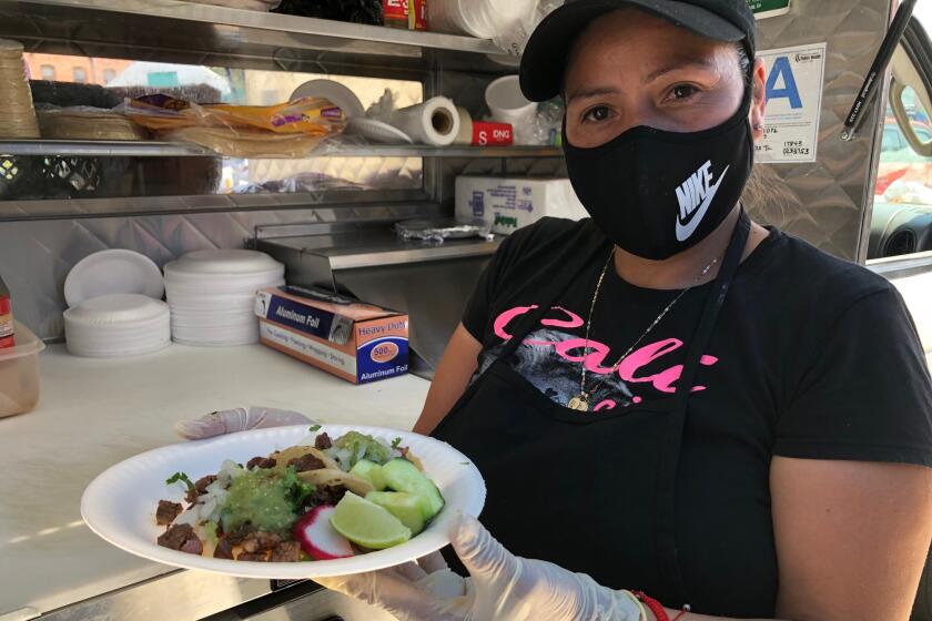 La empresaria Carmen Calles muestra una orden de tacos que fue preparada en su camión de comida.