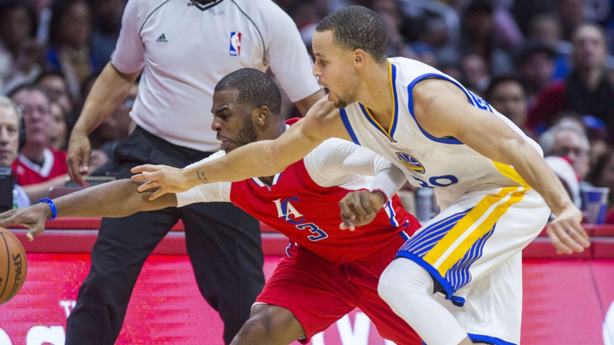 Clippers point guard Chris Paul, left, and Golden State Warriors guard Stephen Curry battle for a loose ball during the Clippers' 100-86 win on Dec. 25.