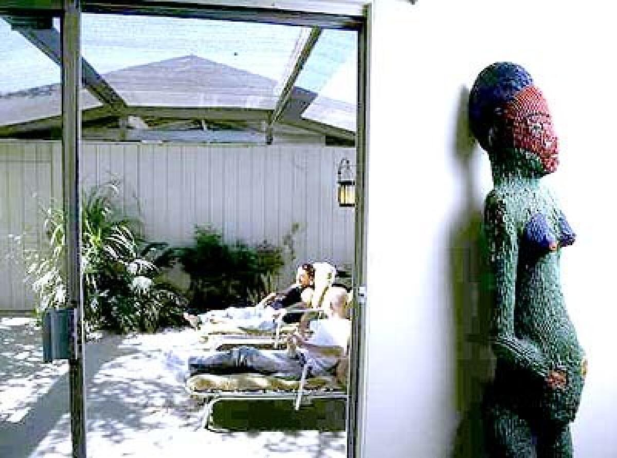 Larry Lazzaro, left, and Bob Weis in their Palm Springs home, which showcases African pieces like this shrine figure from Cameroon.