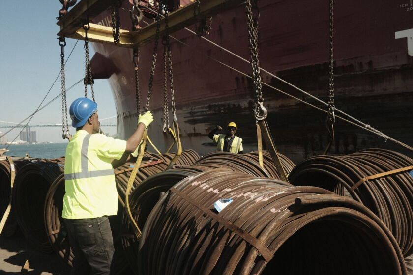 Workers unload bar-in-coil steel from a freight ship in the dockyard at the Port of Detroit in Detroit, Michigan.