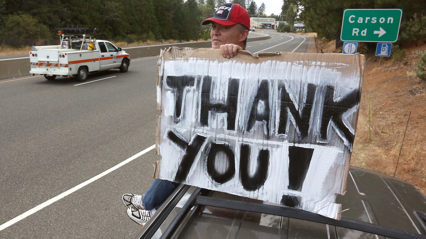 Herve Leconte sits atop his vehicle alongside Highway 50 near Camino, Calif., on Sept. 18, displaying a sign thanking all those who are dealing with the King fire.