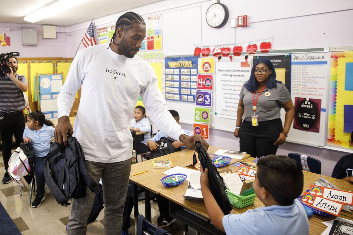 Clippers Kawhi Leonard gives backpacks away to students at One Hundred Seventh Street Elementary School on Tuesday in the Watts neighborhood of Los Angeles.