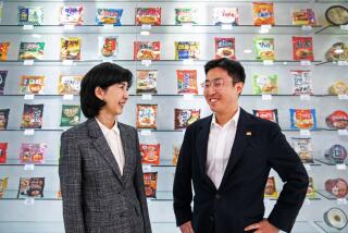 SEOUL, SOUTH KOREA - Kim Jung-soo, left, CEO and Vice Chairperson - who is credited with coming up with the idea for Buldakmyun (fire chicken noodles) - and her son, Chun Byeong-woo, right, a junior vice president who will one day inherit the company, in front of the collection of Samyang Ramyuns in the company's museum inside their headquarters, Samyang Roundsquare. Samyang Food is on the map of how global interest in "K-food" and the viral fame of one product - fire chicken noodles - changed the company's fortunes overnight. (Jean Chung for the Times)
