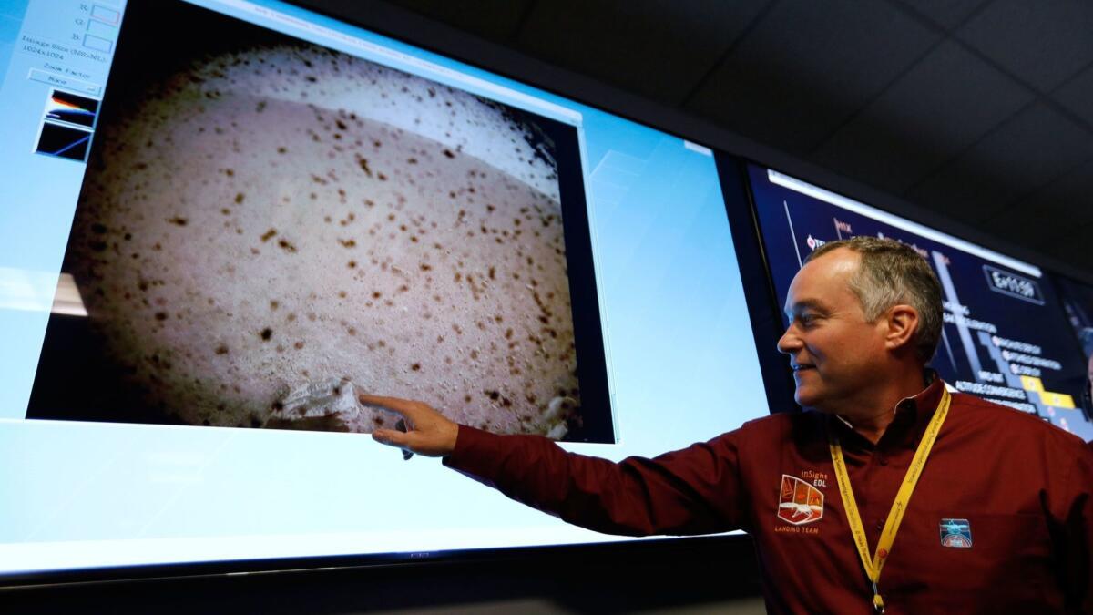 InSight project manager Tom Hoffman points to the first image sent by the Mars Cube One satellites. It shows InSight's landing site, obscured by flecks of dust.