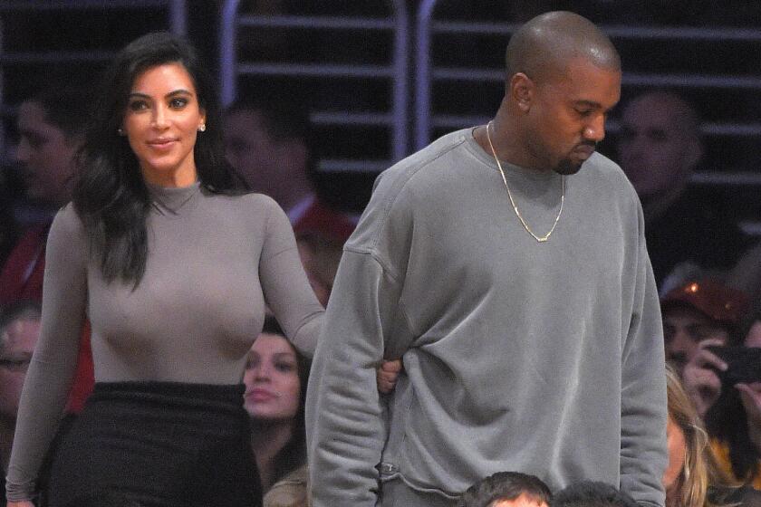 Kim Kardashian, left, and her husband, recording artist Kanye West, watch the Lakers play the Houston Rockets at Staples Center on Oct. 28, 2014.