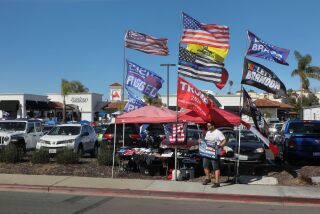 San Marcos, CA - March 12: Conservative memorabilia vendor Ryan Priest, of Escondido, mans his booth on the sidewalk on Descanso Avenue in front the Awaken Church San Marcos Campus where the The ReAwaken America Tour is taking place. (Charlie Neuman / For The San Diego Union-Tribune)