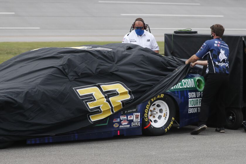 Crews cover the car of driver Corey LaJoie as inclement weather rolls in prior to a NASCAR Cup Series auto race at Talladega Superspeedway in Talladega Ala., Sunday, June 21, 2020. (AP Photo/John Bazemore)