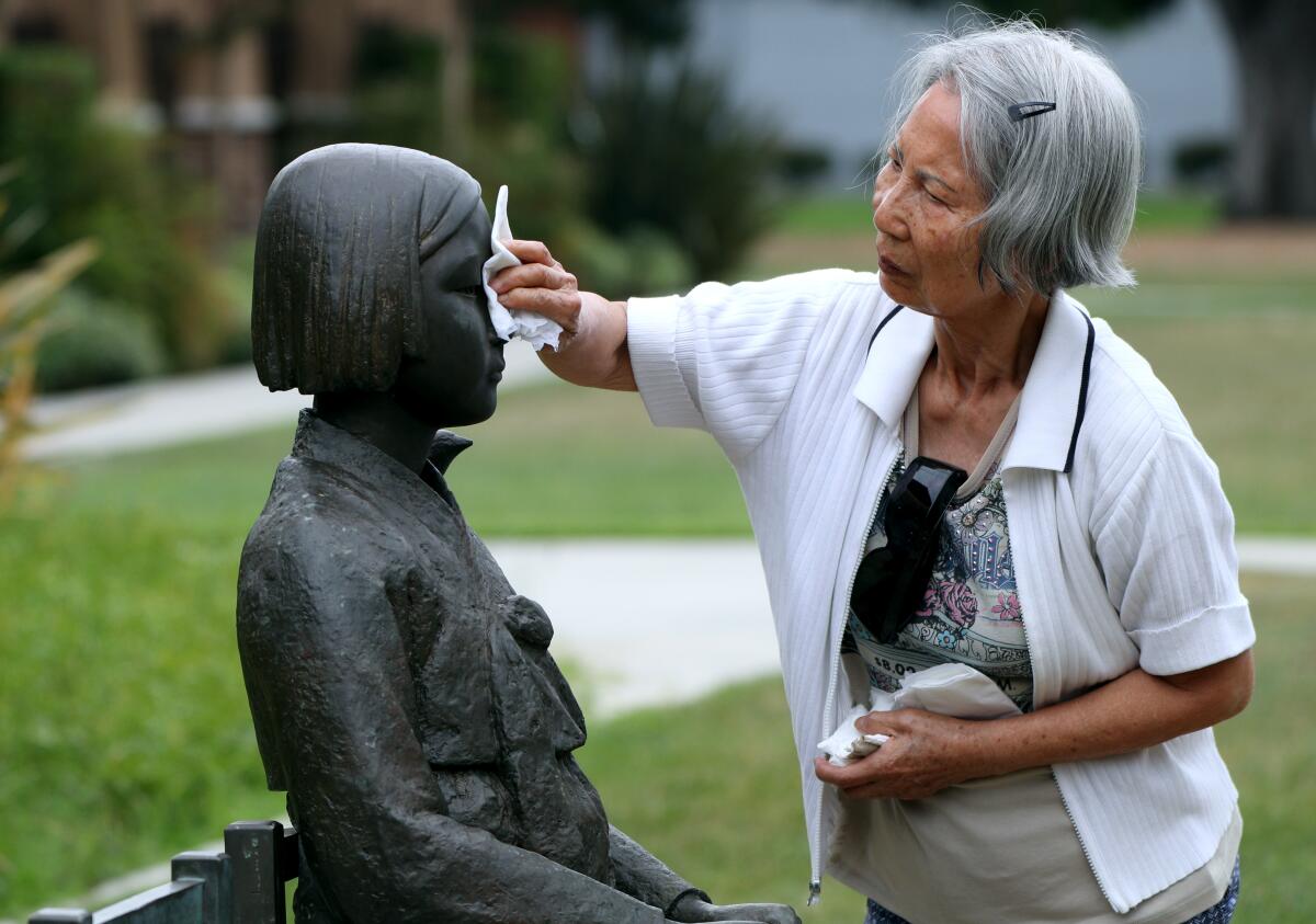 Glendale resident Jean Kuyng Lee, 80, cleans the Korean Comfort Women Peace Monument in Central Park after it was allegedly vandalized with an unknown brown substance on Thursday.