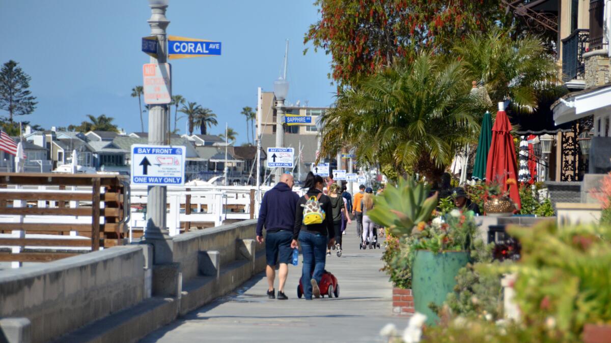People on Balboa Island's wraparound walkway Saturday morning obey the new one-way restriction, which is in place until further notice.