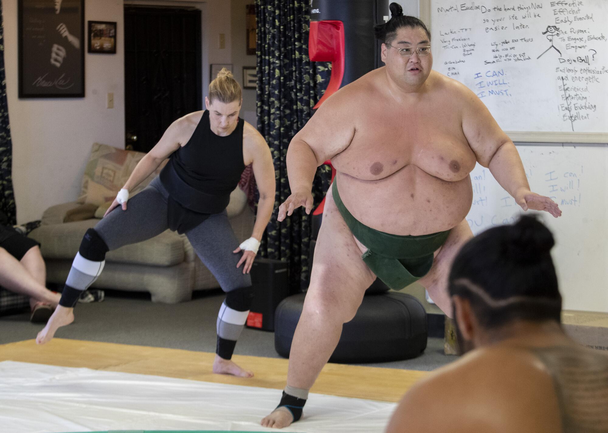 Jenni Crook practices sumo moves as Ryuichi Yamamoto instructs proper technique.
