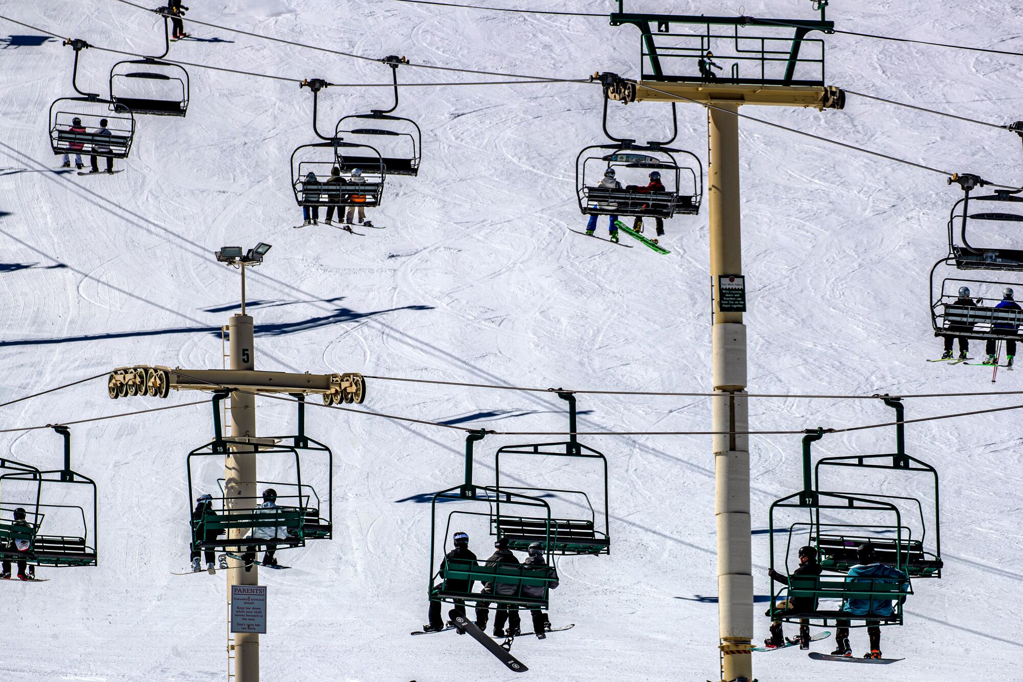 Skiers and snowboarders ride a chairlift at Big Bear Mountain Resort.