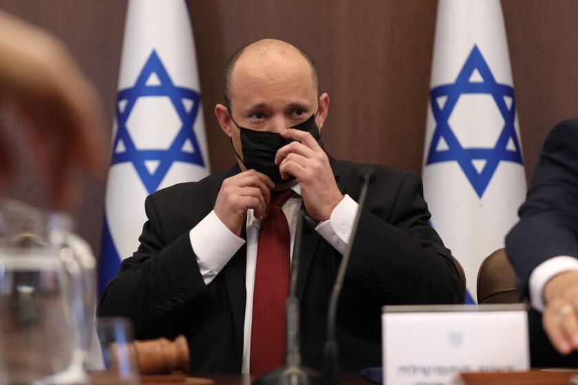 Israeli Prime Minister Naftali Bennett adjusts a face mask as he attends a cabinet meeting at the prime minister's office in Jerusalem, Israel, Sunday, Dec. 19, 2021. (Abir Sultan/Pool Photo via AP)