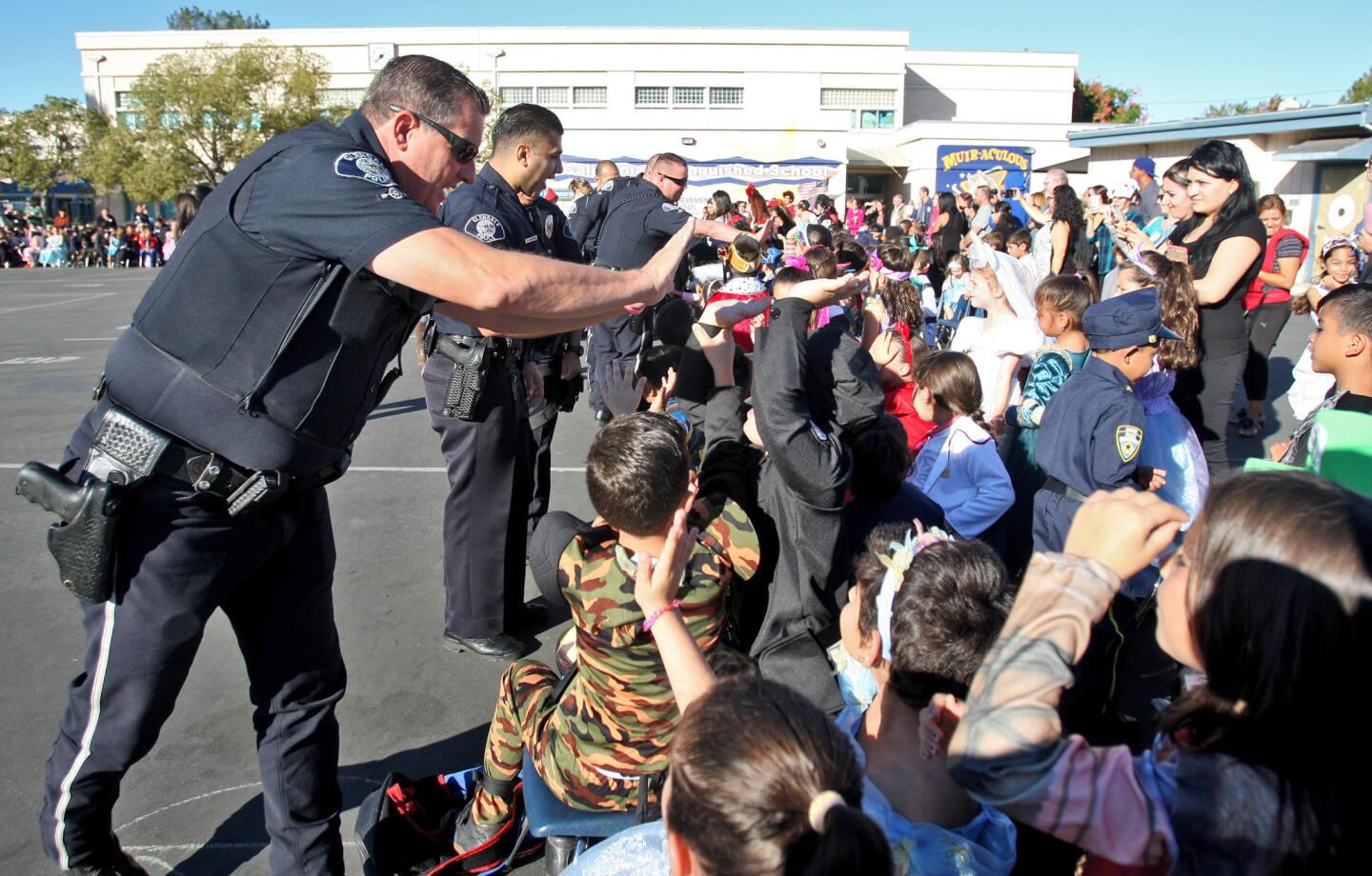 Glendale Police Department officers, including officer Tim Lindner giving high-fives to children, visited John Muir Elementary School during their annual Halloween event in Glendale on Thursday, October 29. 2015. The officers talked about safety for Halloween and also passed out candy bags to 36 classrooms.
