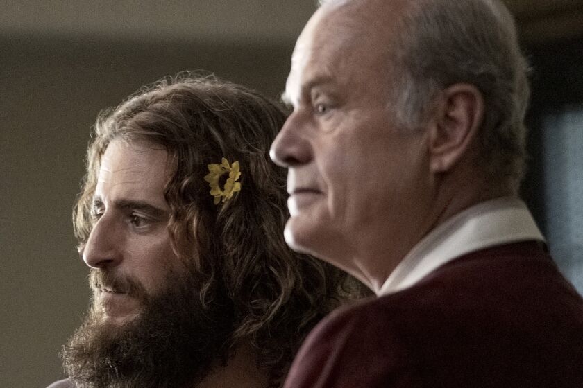 A young man with a beard and a flower in his hair with an older man in the movie "Jesus Revolution."