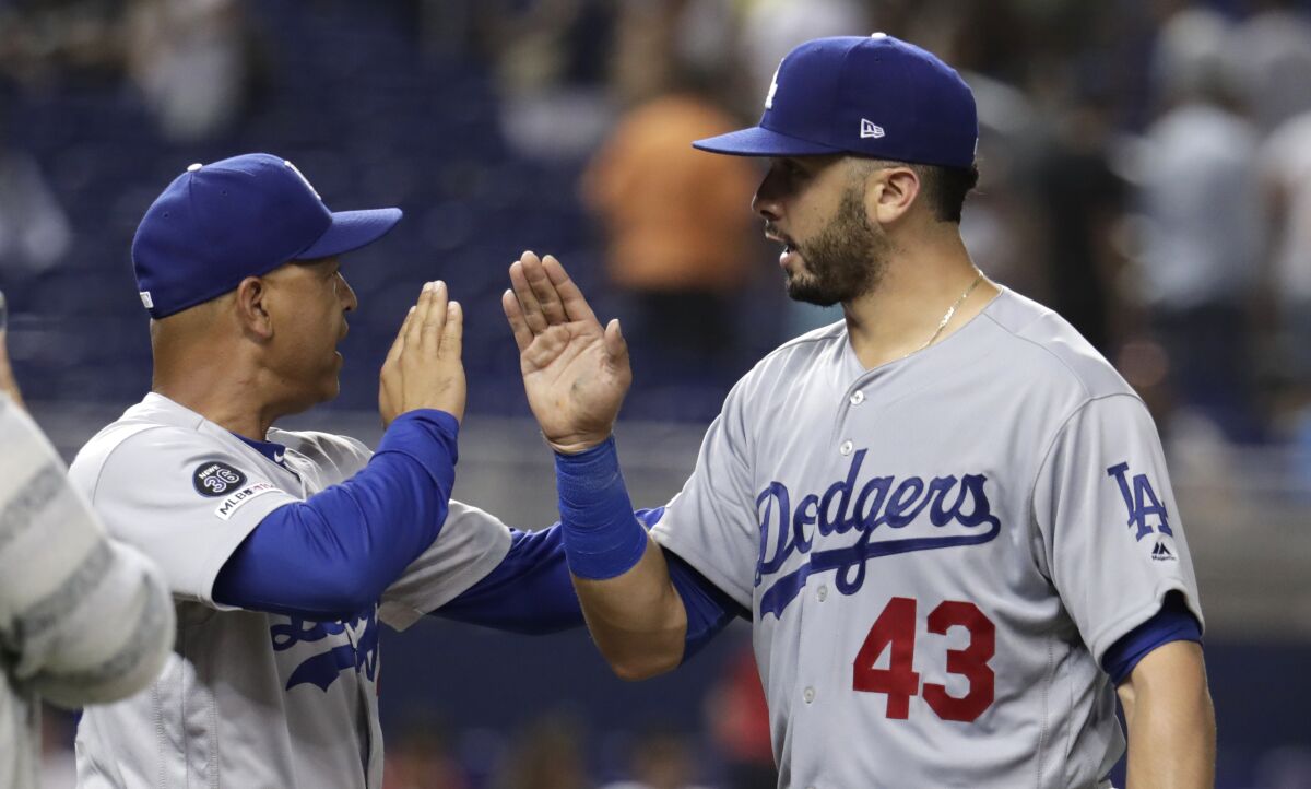 Dodgers manager Dave Roberts, left, high-fives Edwin Rios after defeating the Miami Marlins on Aug. 14 in Miami.
