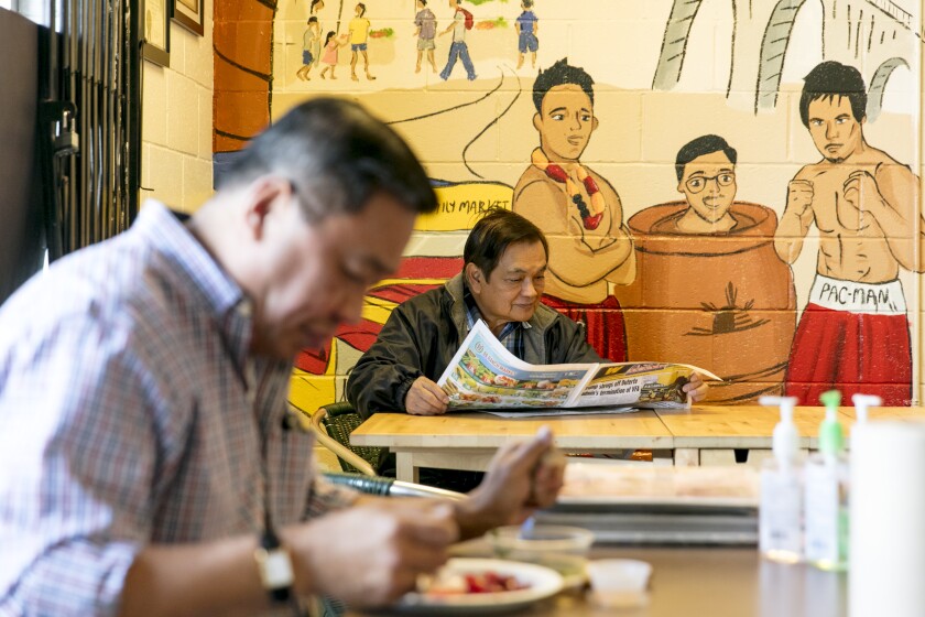 Arturo Esteban reads a newspaper at his family’s market and turo turo restaurant, Chaaste Family Market in Pasadena.