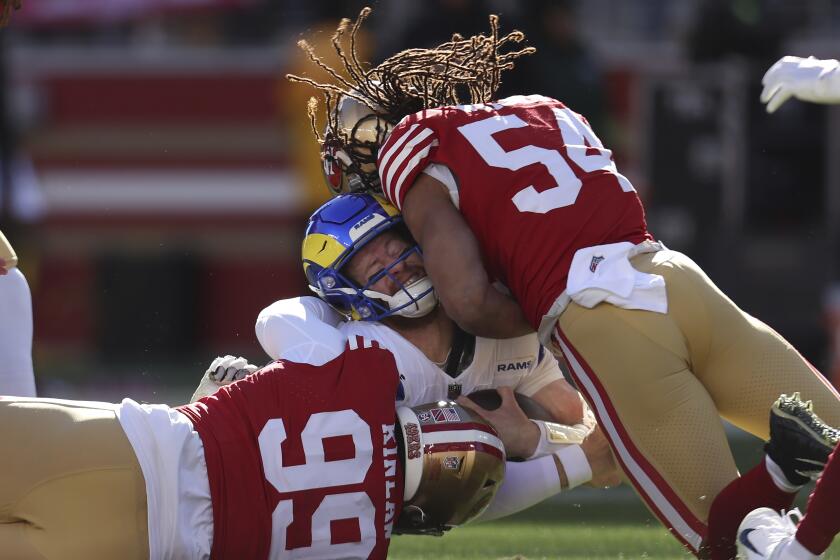 Rams quarterback Carson Wentz is tackled by 49ers Javon Kinlaw (99) and linebacker Fred Warner.