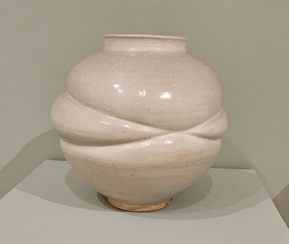 A white porcelain moon jar with indentations left by rope wrapped around it. 