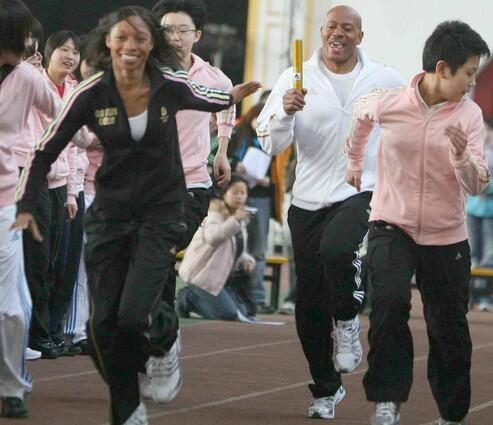 Maurice Greene (2nd R), the Olympic 100m champion in 2000 and three-time world champion in 1997, 1999 and 2001, runs to pass the baton to Allyson Felix (L), the women's 200m world champion in friendly competition against schoolchildren in a promotional campaign on February 4, 2008 in Beijing.