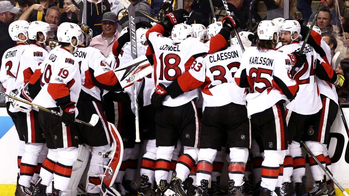Senators players celebrate after Clarke MacArthur (hidden) after he scored the game-winning goal against the Bruins in overtime Sunday.