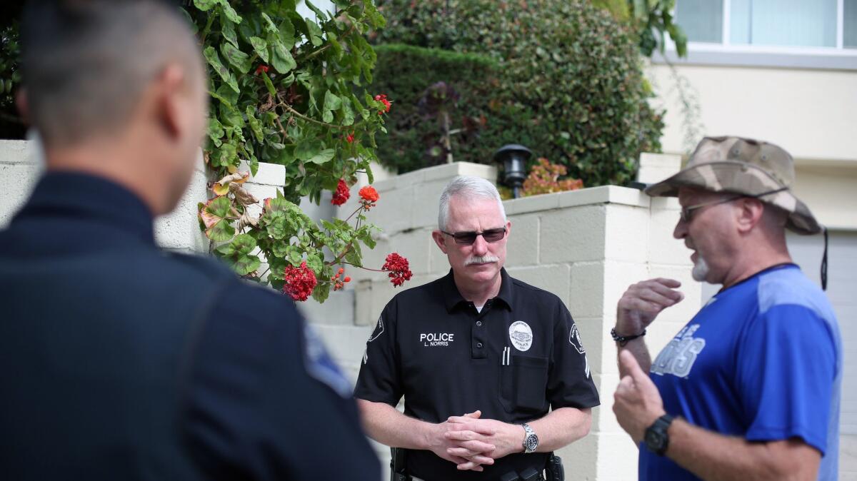 Officer Lee Norris, center, speaks to Eric Blomgren about a neighbor with a history of mental illness.