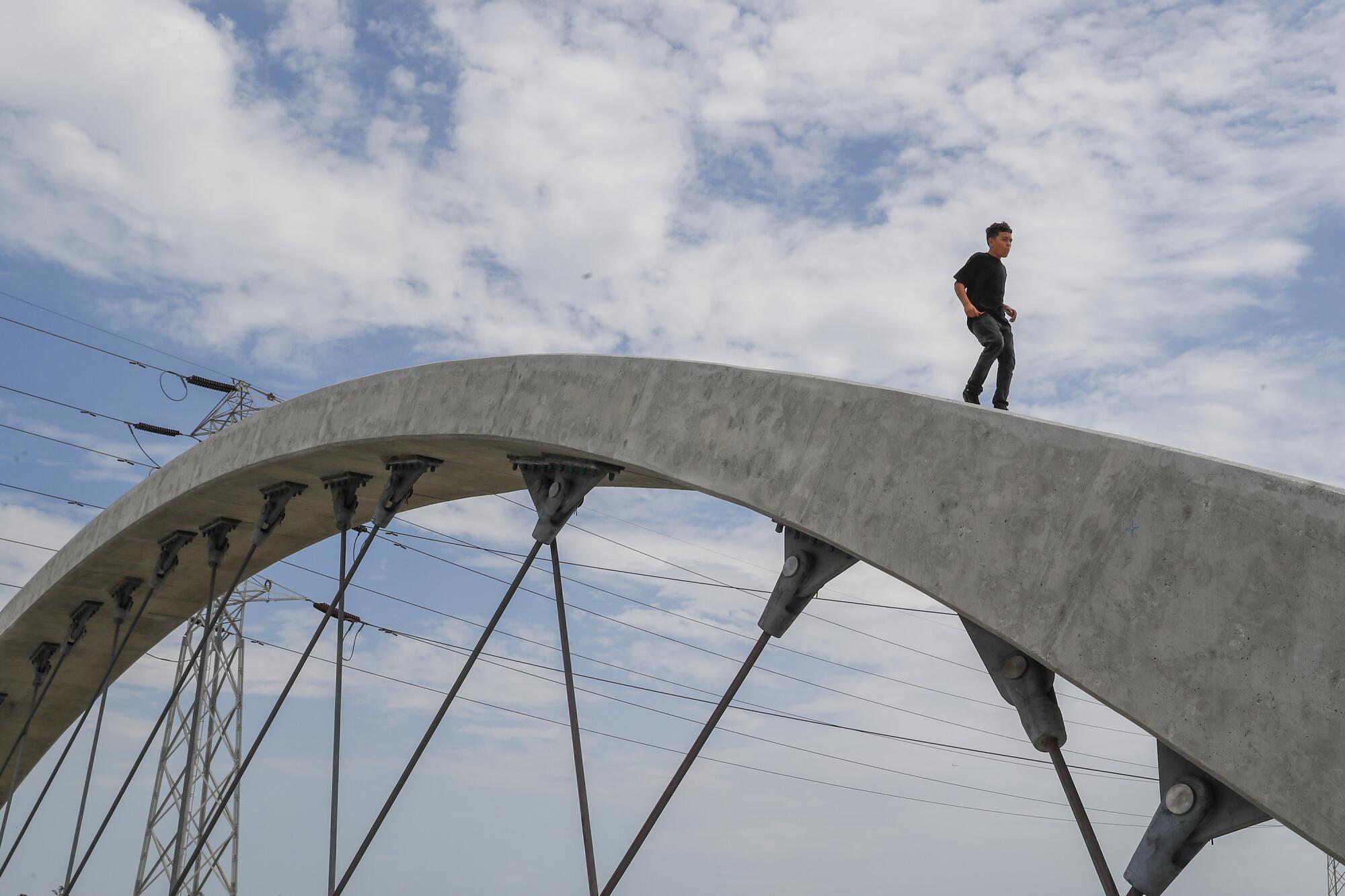 A person climbs on top of one of the arches on the 6th Street Viaduct.