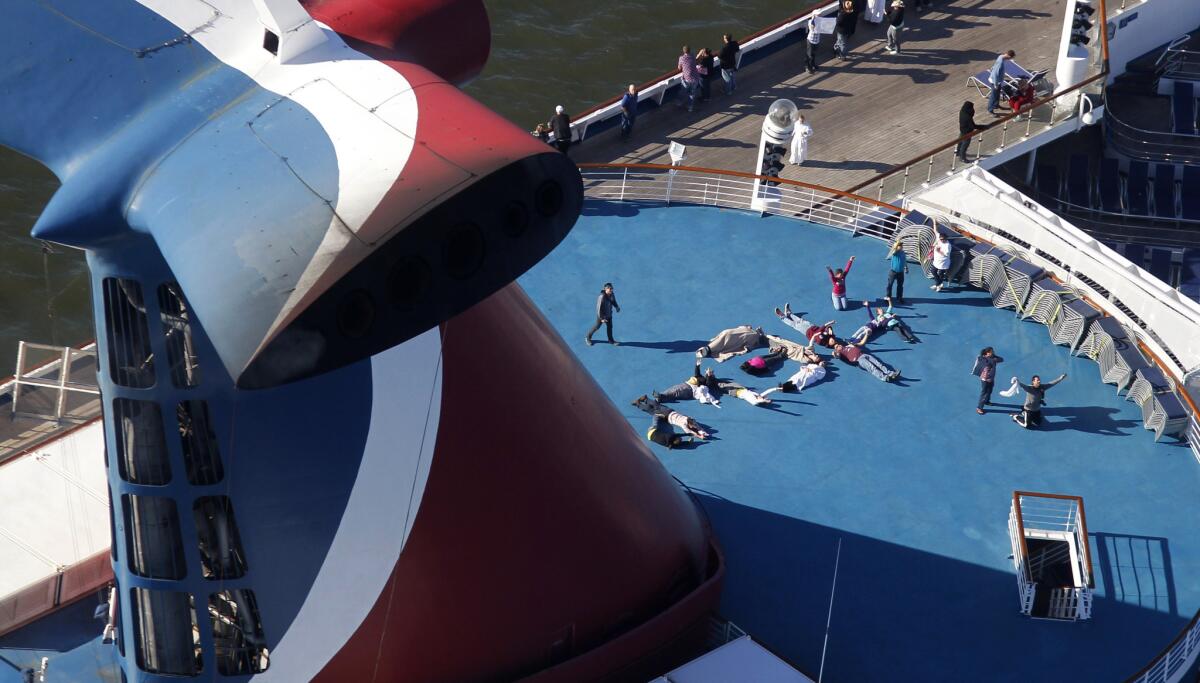 Passengers lying on deck spelled out "HELP" aboard the disabled Carnival Lines cruise ship Triumph as it was towed to harbor off Mobile Bay, Ala., on Valentine's Day 2013. Carnival Corp. is reporting higher revenue and earnings for the second fiscal quarter of 2014.