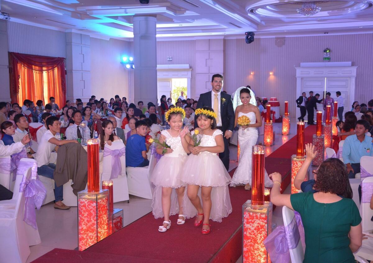 Following their traditional Vietnamese ceremony, Nhu Le and Alex Sarkisian made a grand entrance to their reception at a wedding hall in Da Nang, Vietnam. The ceremony was held at the home of Le's parents. The flower girls here are Le's cousins, Hien Thi Thao Nguyen (left) and Phuong Thi Uyen Phan. — Tran Van Lai