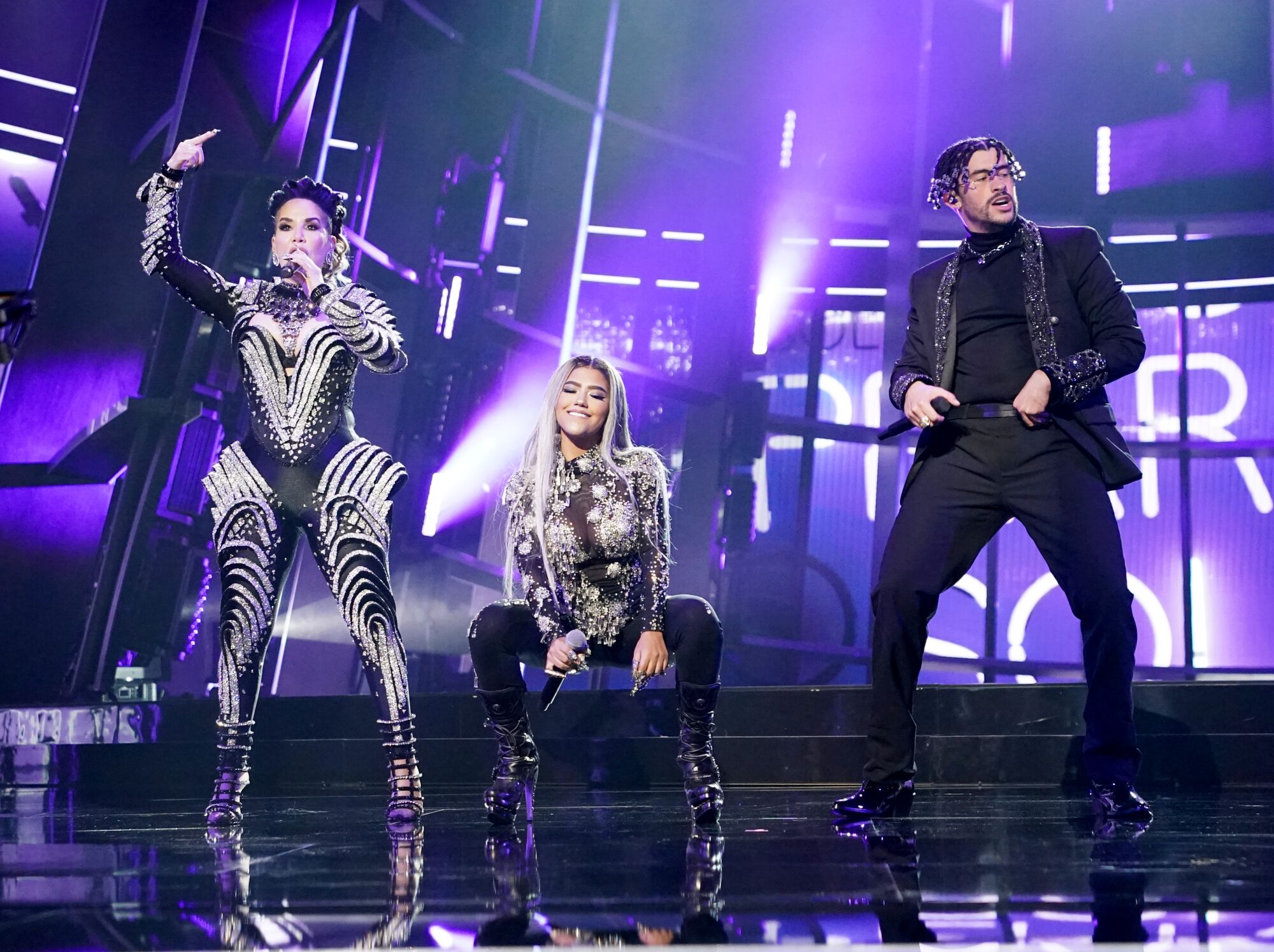  Ivy Queen, Nesi and Bad Bunny, in silver and black, perform on stage. 