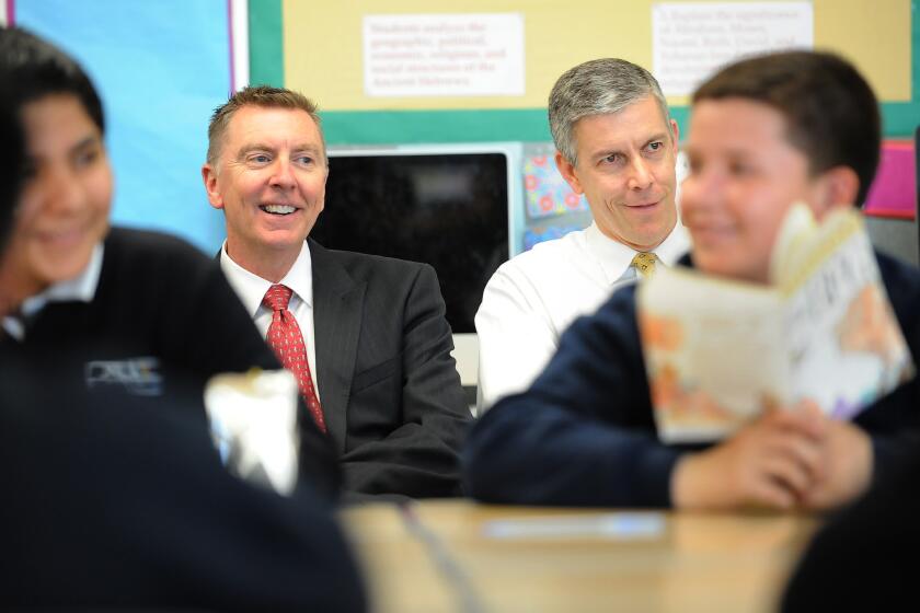 Former L.A. Unified schools Supt. John Deasy, left, and U.S. Secretary of Education Arne Duncan listen to a reading class at Dr. Julian Nava Learning Academy in Los Angeles in 2014. Duncan is stepping down from his post in December.
