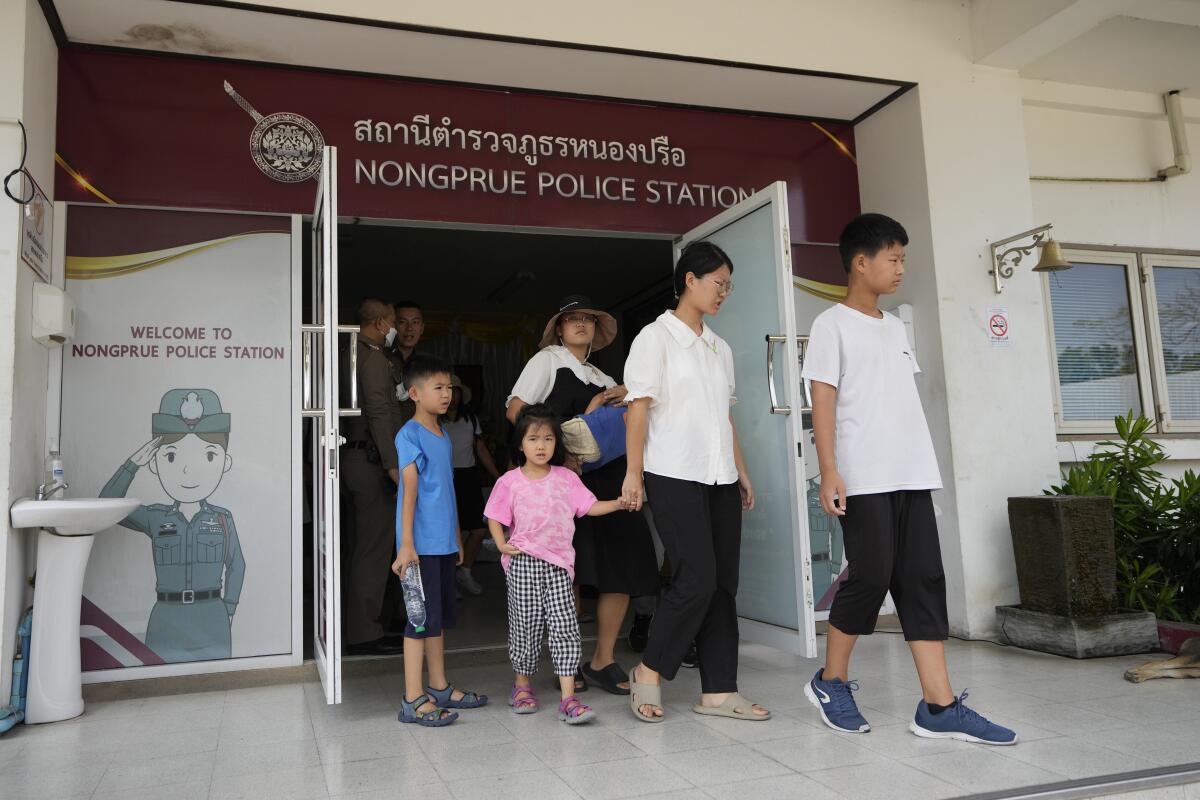 Adults and children leaving a police station in Thailand