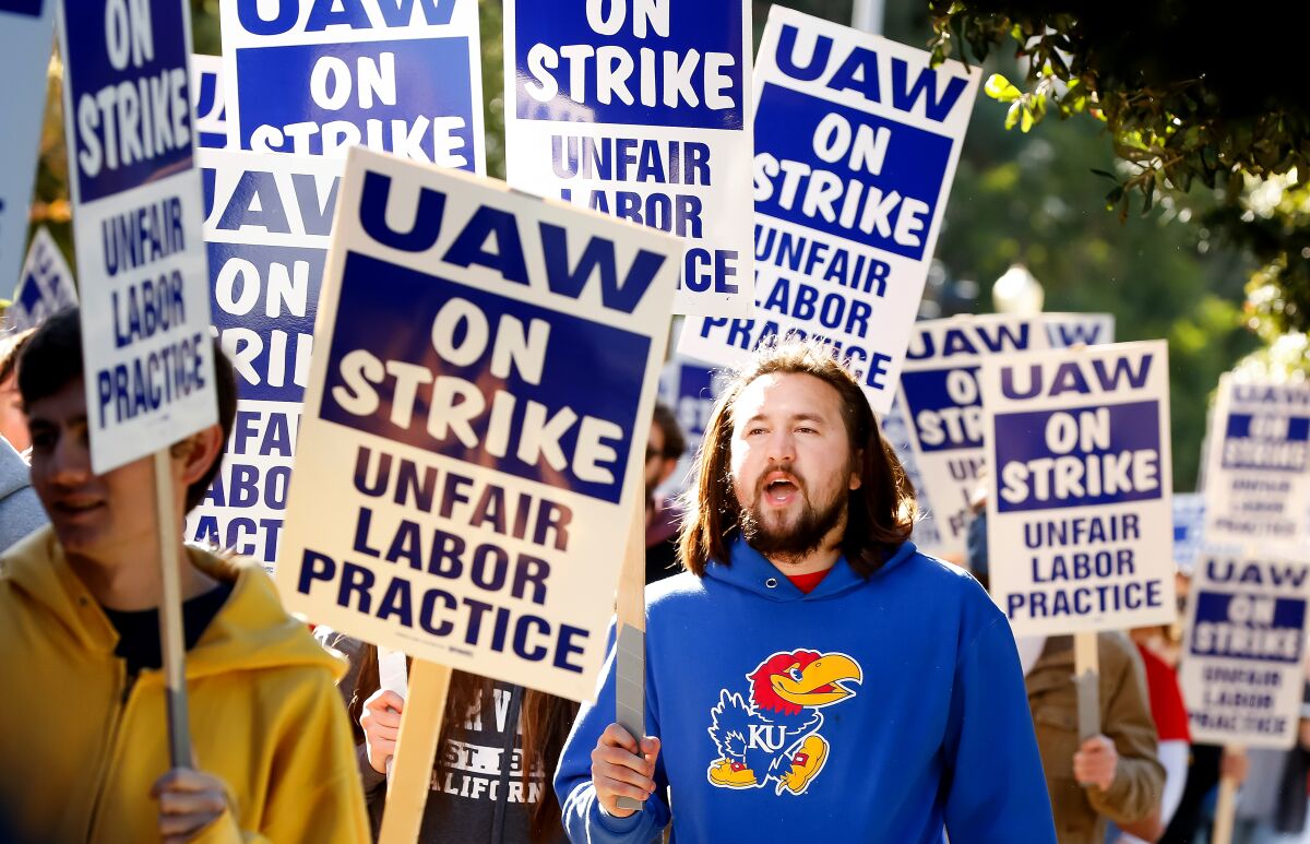 A man joins picketers holding signs.