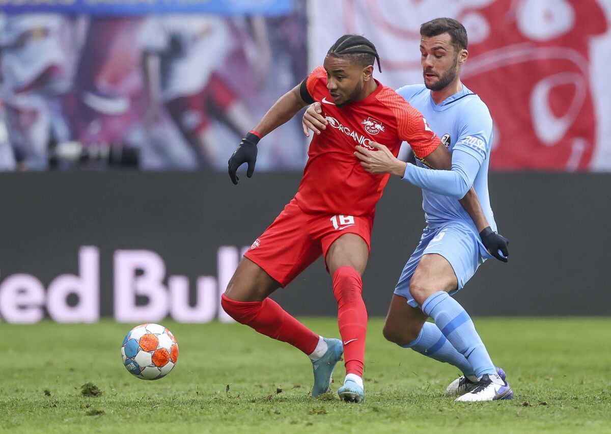 Freiburg's Manuel Gulde, right, and Leipzig's Christopher Nkunku, left, challenge for the ball during the German Bundesliga soccer match between RB Leipzig and SC Freiburg in Leipzig, Germany, Saturday, March 5, 2022. (Jan Woitas/dpa via AP)