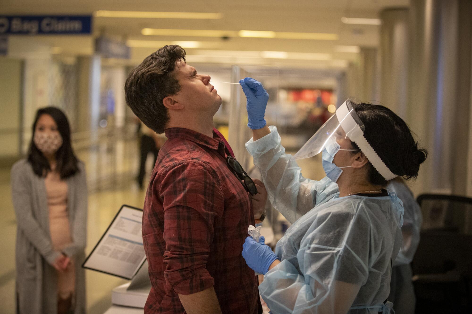 Elizabeth Cameros administers a deep nasal swab to traveler Wade Hopkins for coronavirus testing at LAX.