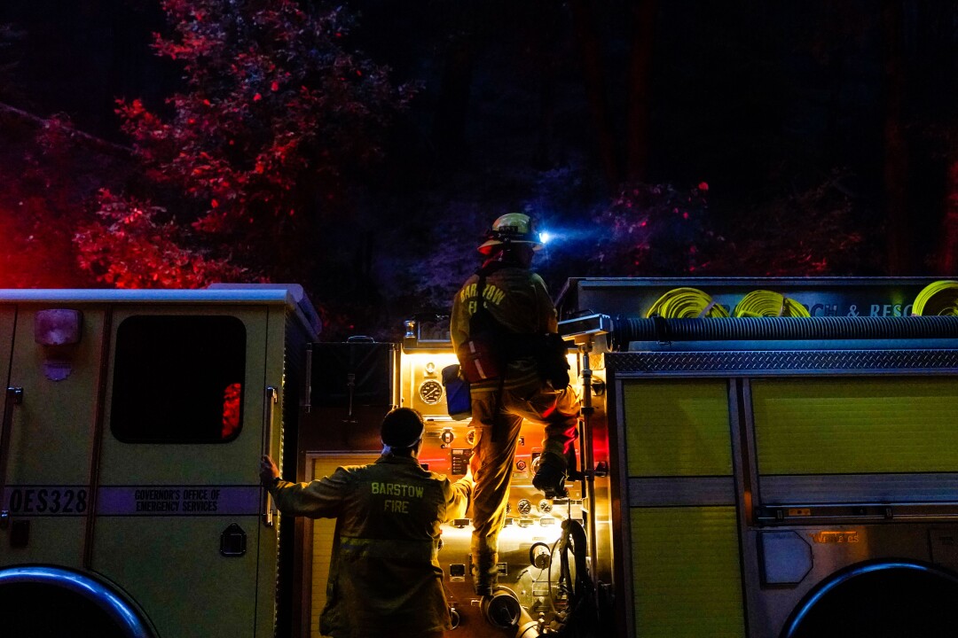 Firefighters on a fire truck at night