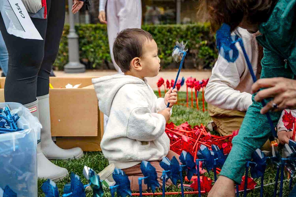 A child holds a pinwheel during CASA OC's annual Pinwheel Project fundraiser, supporting foster care youth.