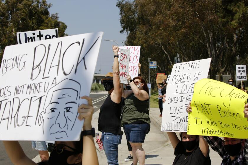 Protesters hold signs during a Black Lives Matter rally at Bonita Creek Park in Newport Beach on Saturday, June 20, 2020. About three dozen protesters were at this peaceful rally.