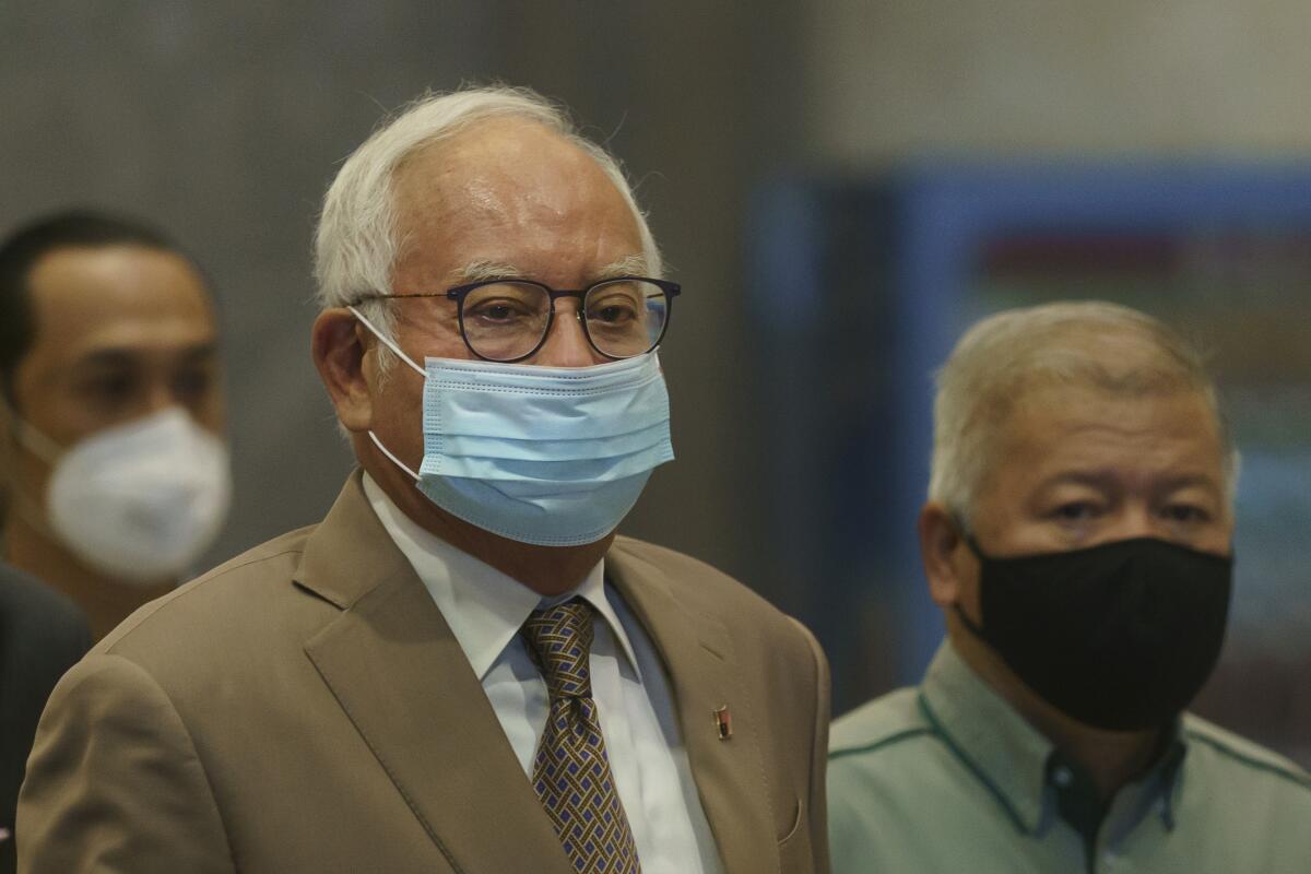 Former Malaysian Prime Minister Najib Razak, center, wearing a face mask arrives at Court of Appeal in Putrajaya, Malaysia, Monday, April 5, 2021. The court Monday began hearing an appeal by Najib to overturn his conviction and 12-year jail sentence linked to the massive looting of the 1MDB state investment fund that brought down his government in 2018. (AP Photo/Vincent Thian)
