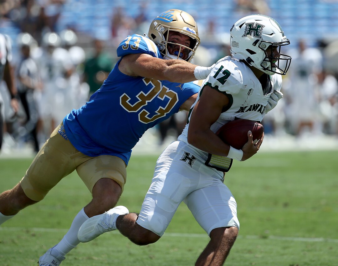 UCLA linebacker Bo Calvert chases down Hawaii quarterback Chevan Cordeiro.