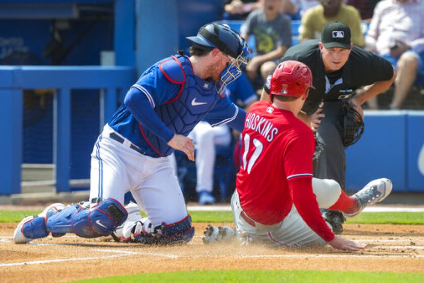 Philadelphia Phillies' Rhys Hoskins is out at home plate with the tag by Toronto Blue Jays catcher Danny Jansen in the first inning of their spring training baseball game in Dunedin, Fla., Sunday, March 5, 2023. (Fred Thornhill/The Canadian Press via AP)