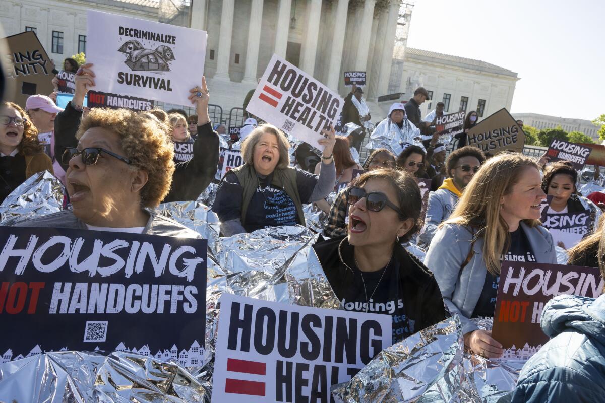 People outside Supreme Court hold signs that read "Housing not handcuffs"