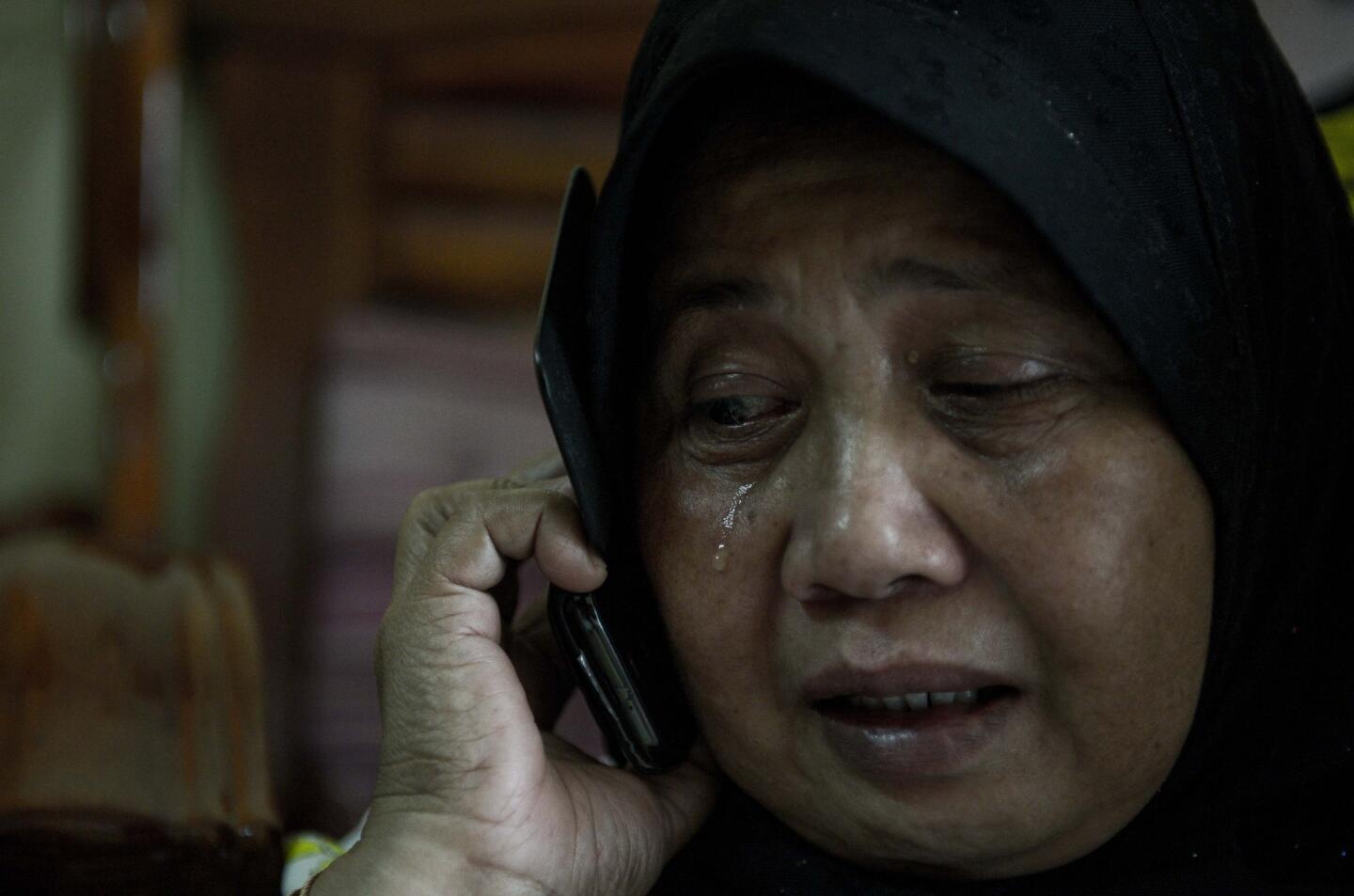 A relative of Norliakmar Hamid and Razahan Zamani, passengers on a missing Malaysia Airlines Boeing 777-200 plane, cries at their house in Kuala Lumpur.
