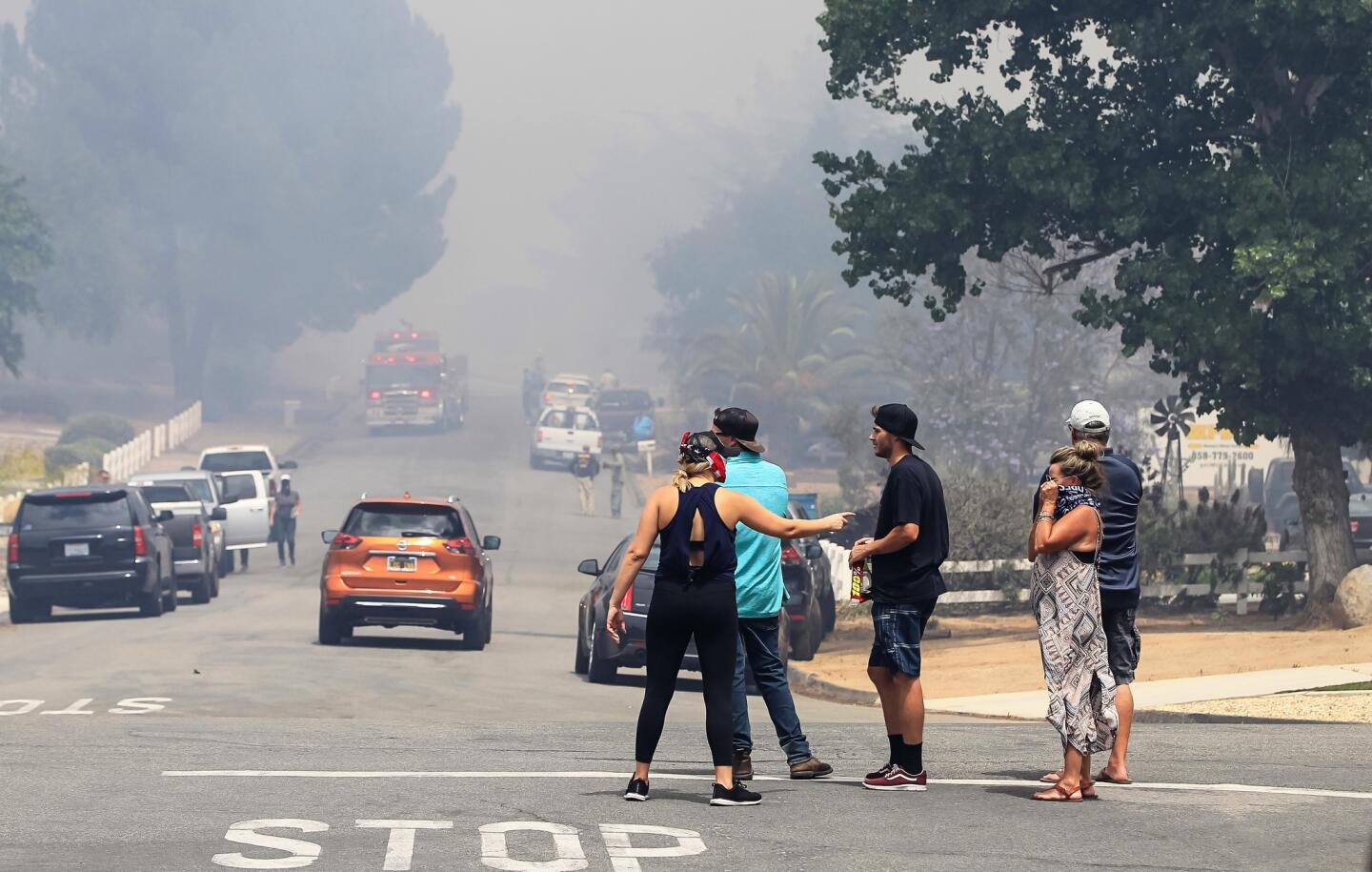 Residents watch fire activity standing at the corner of Highlands View Road and Viejas View Place on Friday during a fire in Alpine, California.