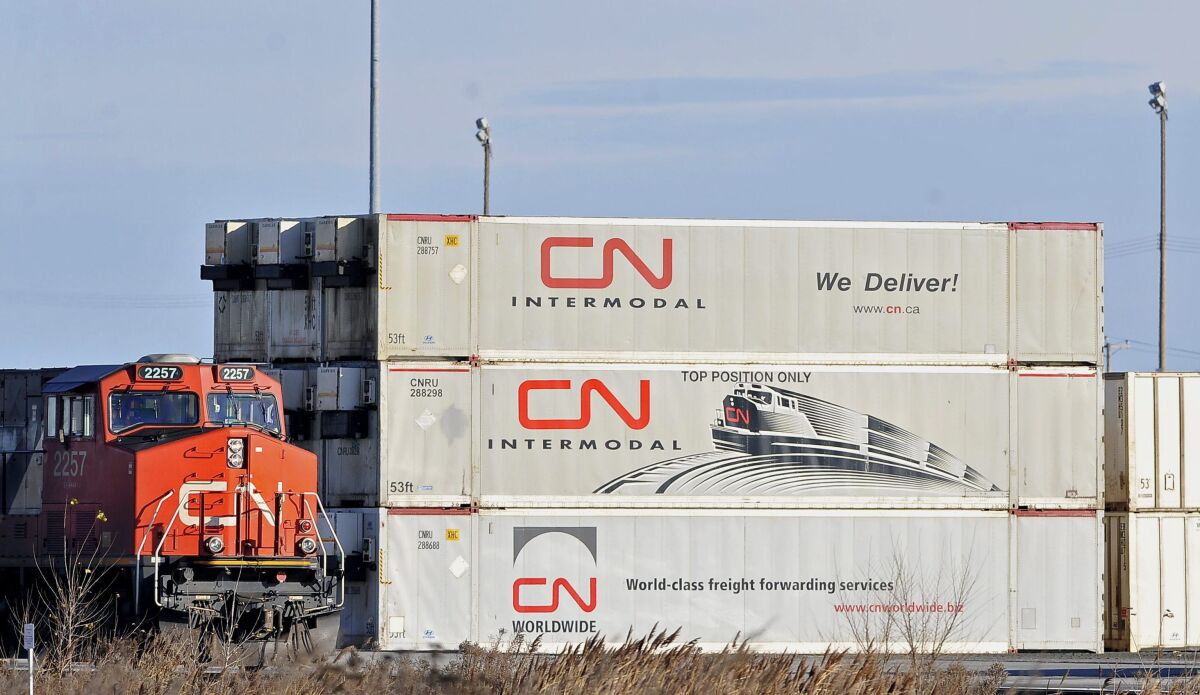 A Canadian National locomotive passes by freight containers at the Canadian National Taschereau yard in Montreal, Saturday, Nov. 28, 2009. Canadian National sweetened its offer to buy Kansas City Southern railroad Thursday, May 13, 2021, and derailed rival Canadian Pacific’s bid for the railroad that handles traffic in the United States and Mexico. (Graham Hughes/The Canadian Press via AP)